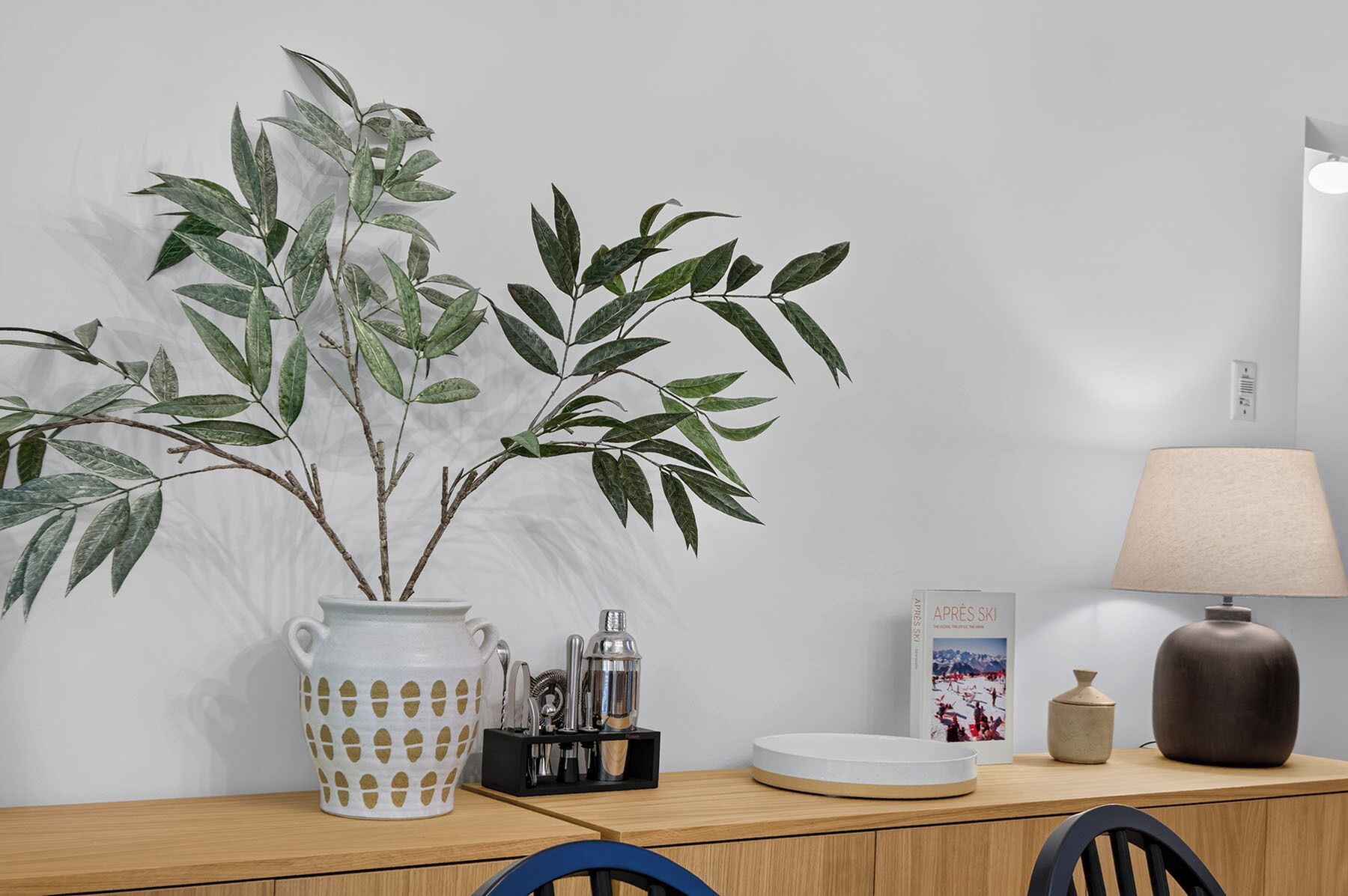 Een houten tafel met een bloempot, een lamp, een boek en een decoratieve vaas.