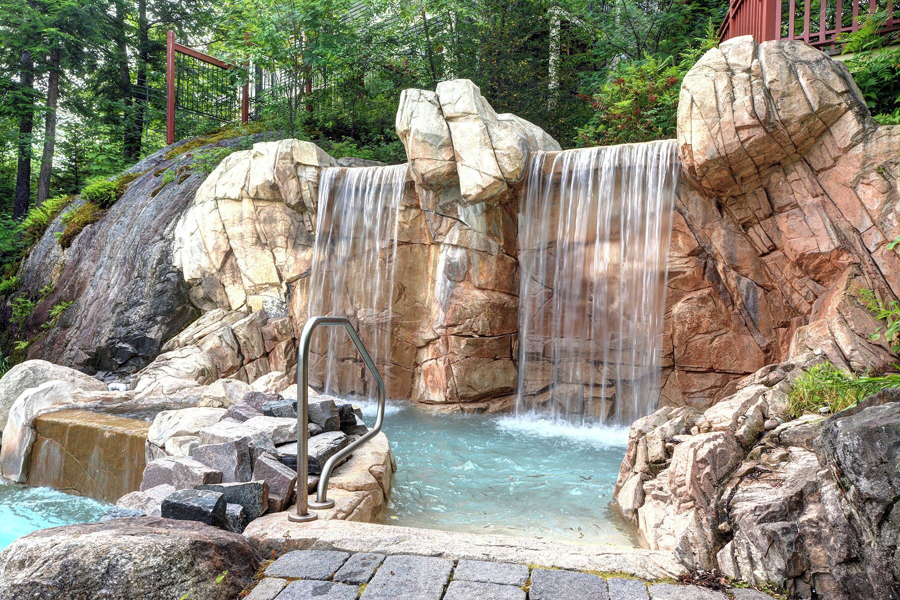 A natural rock formation with a waterfall and a pool.