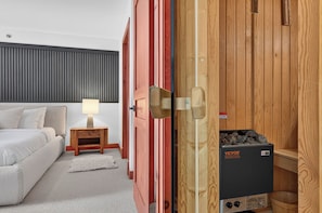 A hotel room with a bed, bedside table, lamp, and a wooden wardrobe with a heater. - 205 Les Eaux Unit 7 (Mont-Tremblant)
