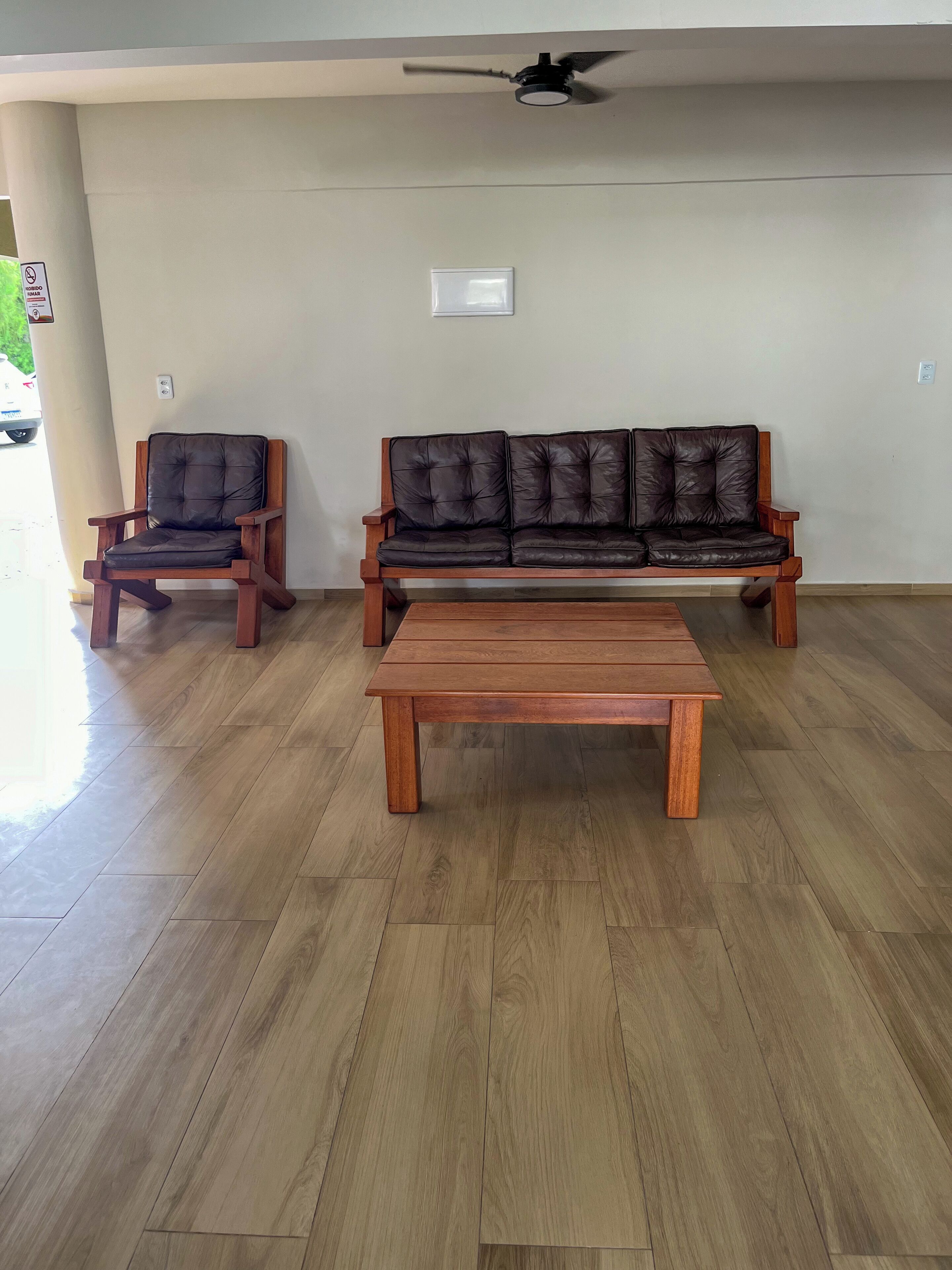 Una habitación con piso de madera, un sofá, una silla y una mesita de centro.