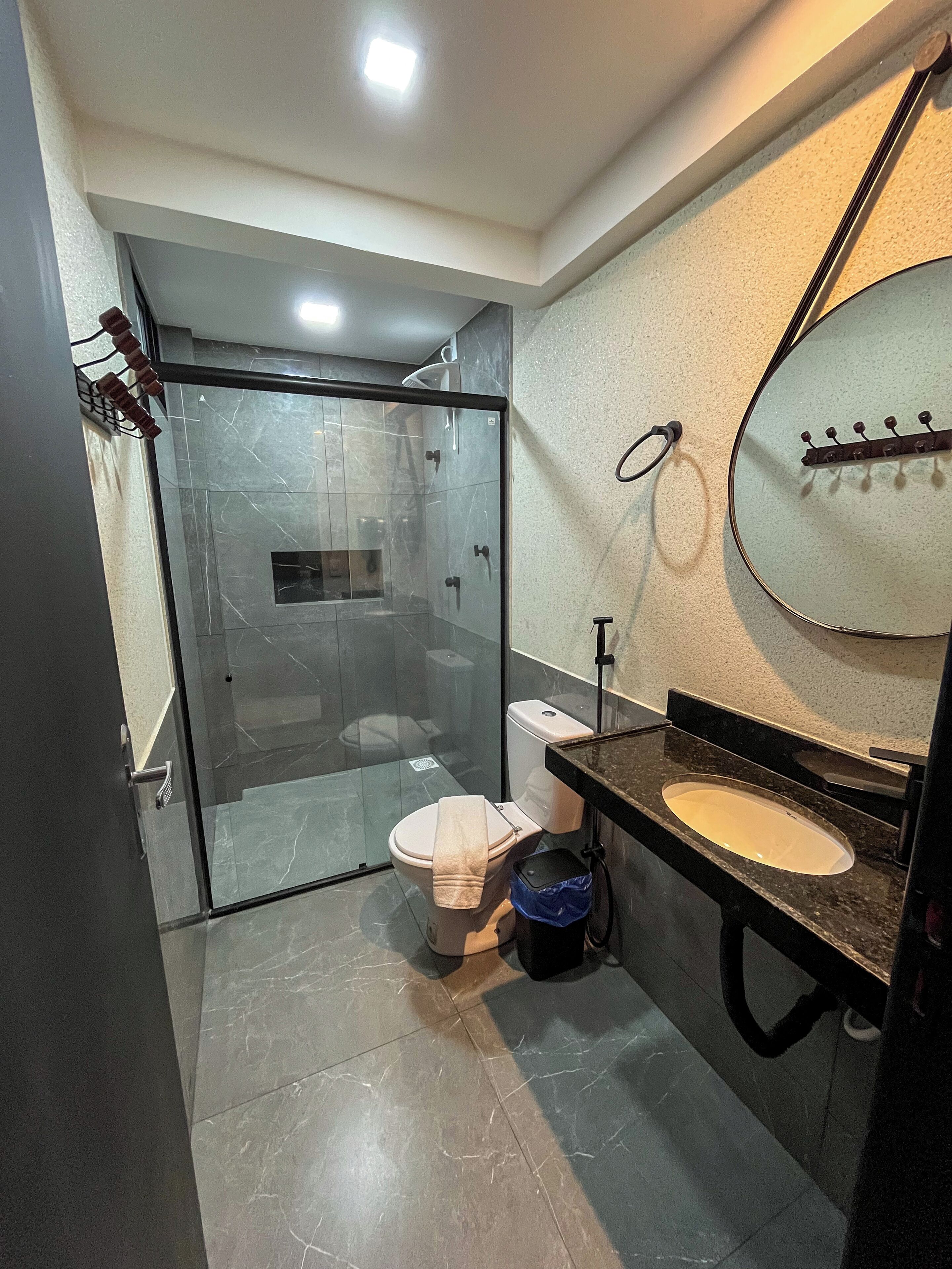Un baño moderno con ducha envuelta en vidrio, inodoro y lavabo con espejo.
