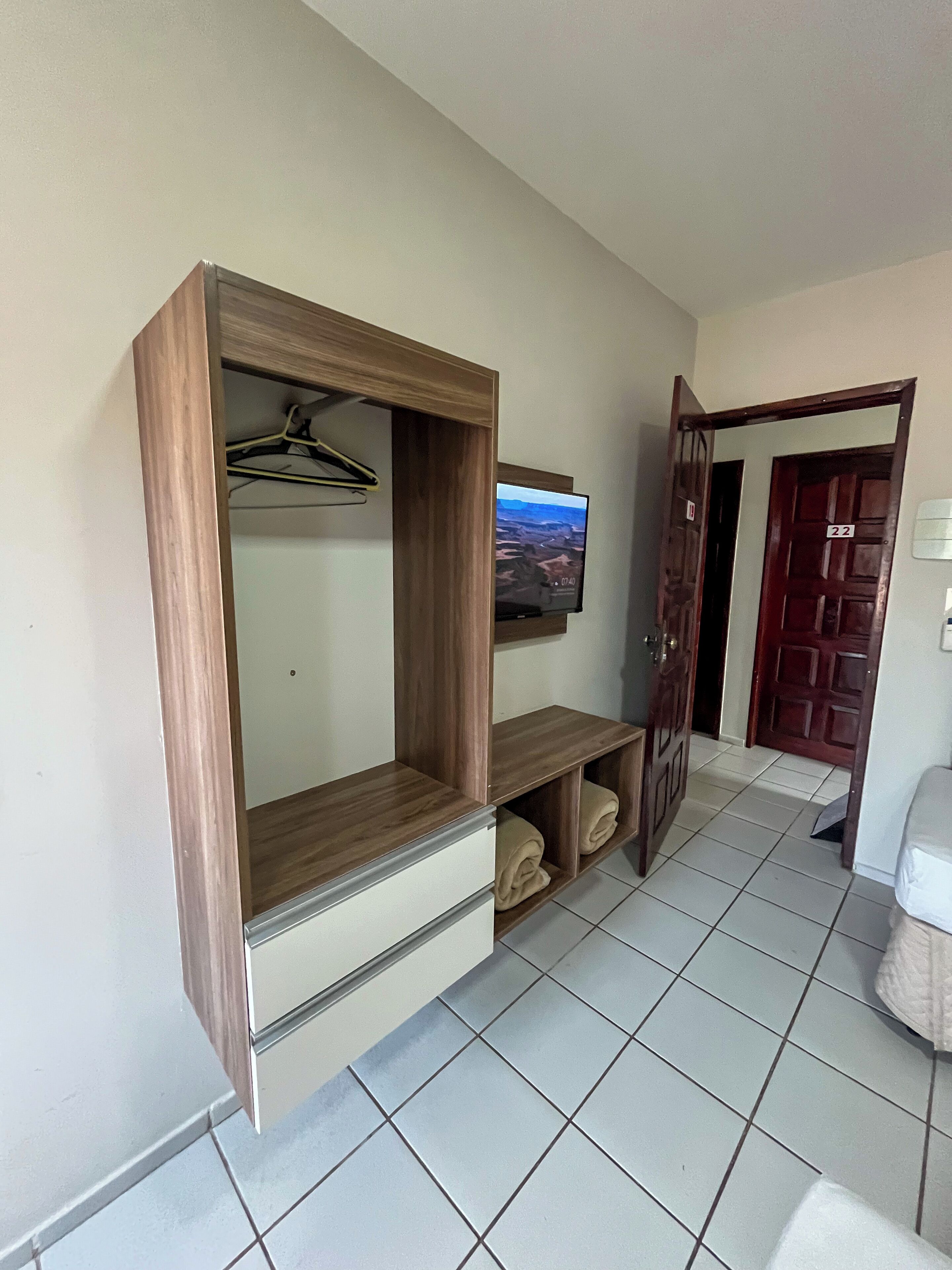 A hotel room with a wooden entertainment unit, a television mounted above it, and a door labeled with the number 22.
