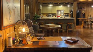 Un interior de madera acogedor con una mesa de comedor central, un mapa mundial en la pared y un cartel de bienvenida para mascotas.