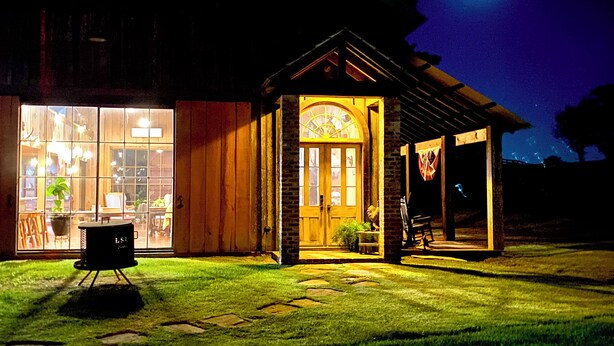 Un edificio de madera con un amplio ventanal y una puerta más pequeña, ambos iluminados.