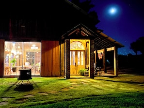 Un bâtiment en bois doté d’une grande fenêtre en verre et d’une porte plus petite, toutes deux éclairées.