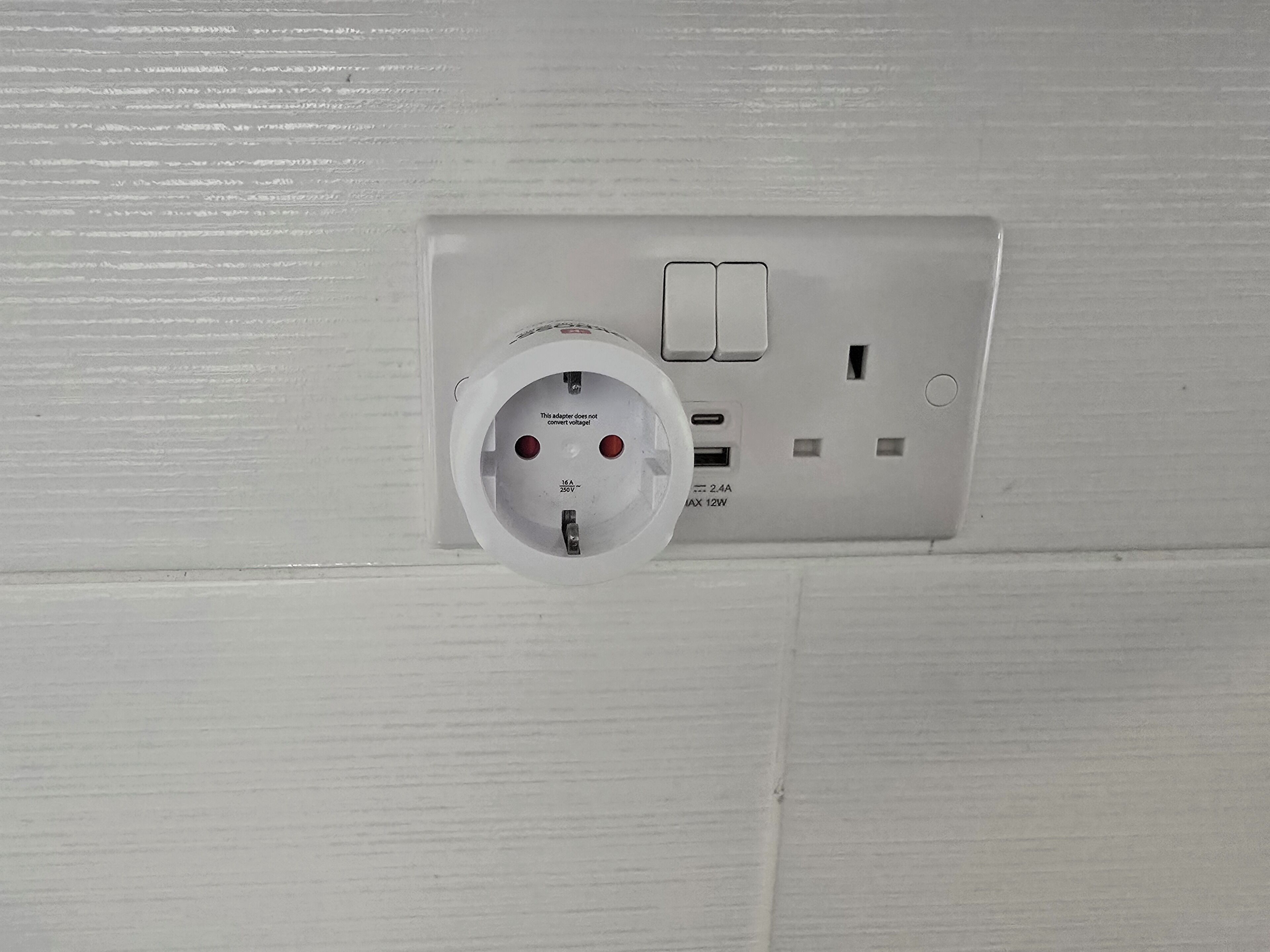 A white electrical outlet with a plug, a switch, and a USB port.