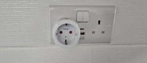 A white electrical outlet with a plug, a switch, and a USB port.