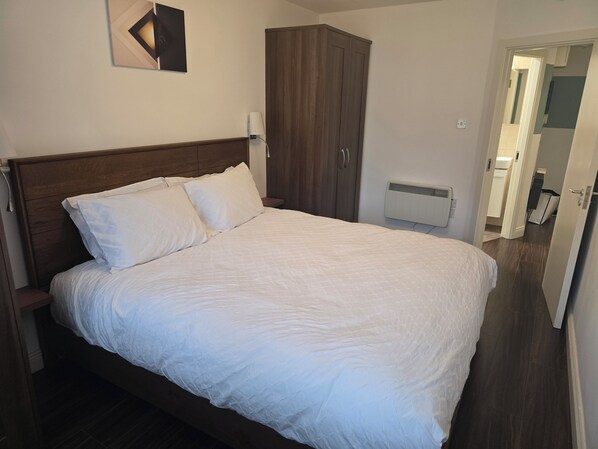 A neatly made bed with white bedding in a room with a wooden headboard and a dark wooden wardrobe. - Free Private Transport From Any Dublin Port (Dublin)