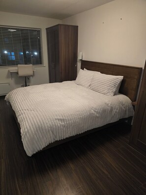 A neatly made bed with a white quilt, a wooden headboard, and a dark wooden wardrobe. - Free Private Transport From Any Dublin Port (Dublin)