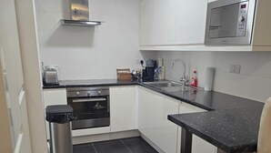 A modern kitchen with white cabinets, a stainless steel range hood, a microwave, and a black countertop. - Free Private Transport From Any Dublin Port (Dublin)