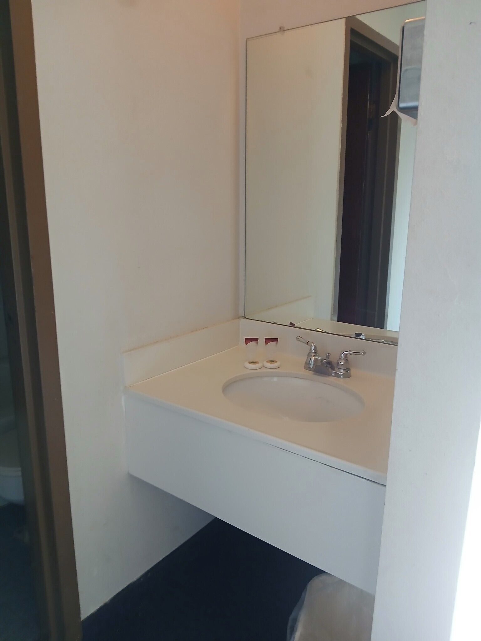 Un baño con un lavabo blanco, un espejo y dos botellas de jabón.