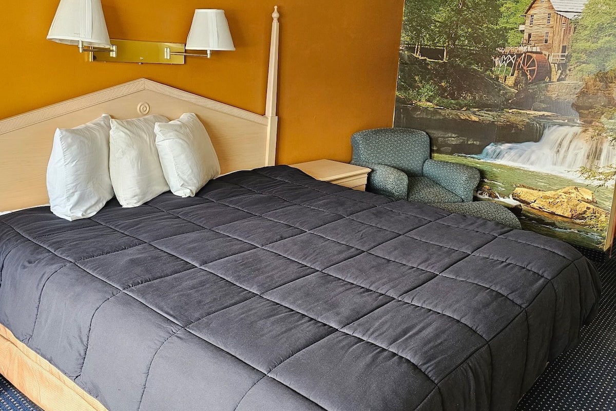 Habitación de hotel con una cama grande, dos lámparas de pared, un cabecero y un mural de un molino de agua.