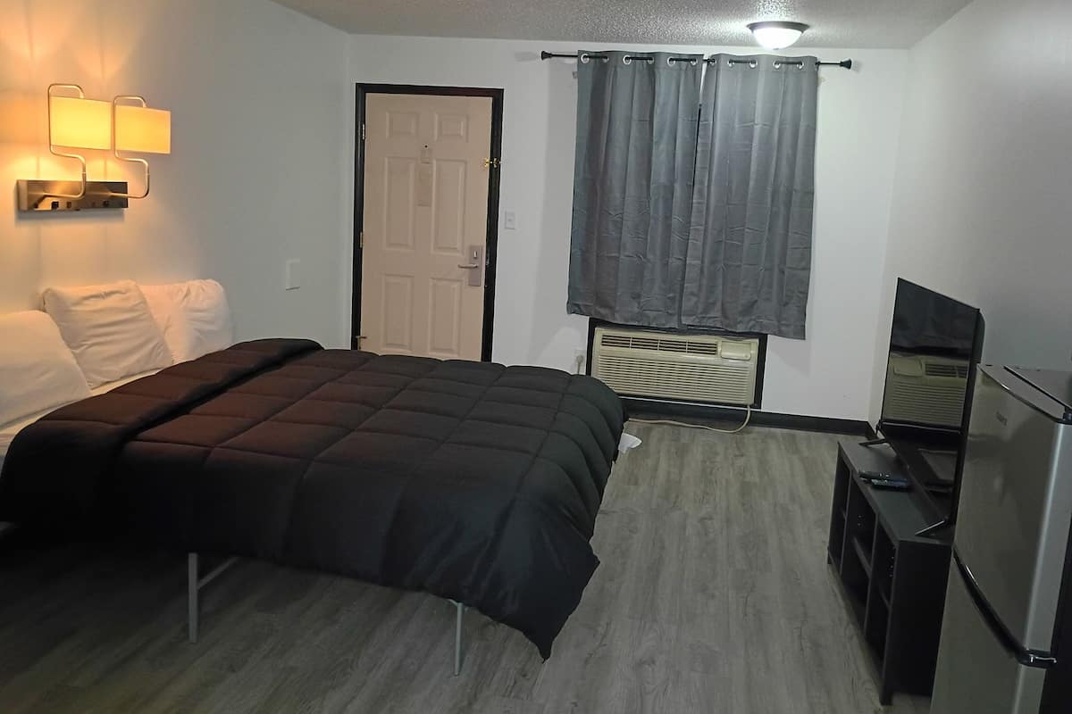 Una habitación de hotel con una cama, un televisor, un calentador y una puerta.