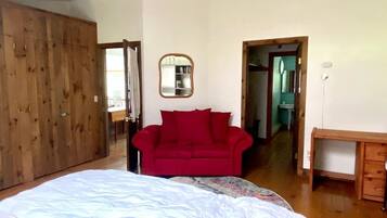 Ein Schlafzimmer mit einem großen Bett, einem roten Sofa, einem Holzschrank und einem Schreibtisch.