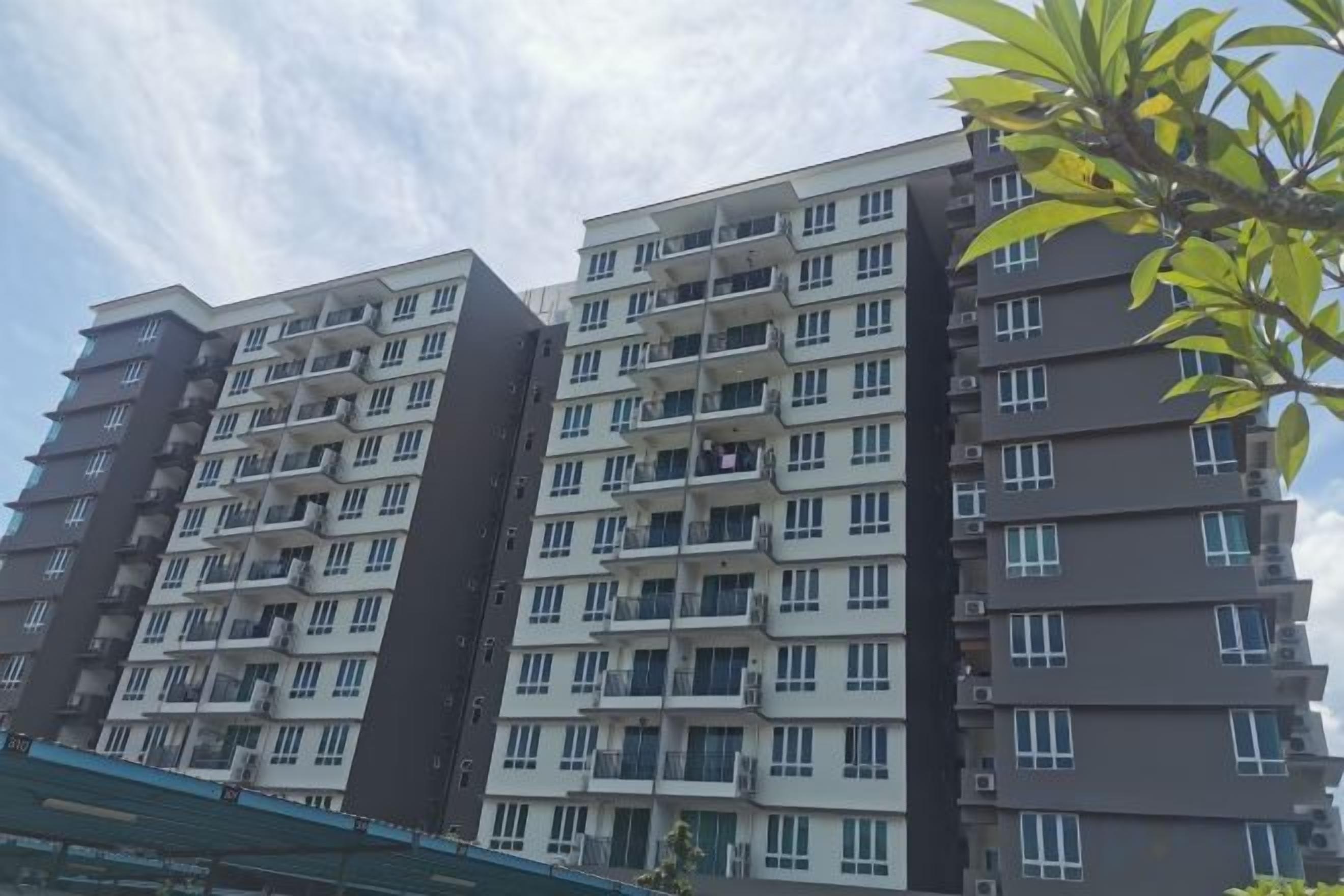 A multi-story residential building with balconies, a flat roof, and a clear sky.