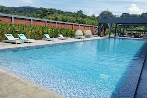 A swimming pool with lounge chairs and a covered area.