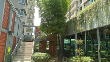 A multi-story building with a central staircase, glass facade, and greenery.