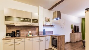 A modern kitchen with wooden cabinets, a built-in oven, and a coffee maker. - Luxuriose Ferienwohnung am Stormthaler See (Grossposna)