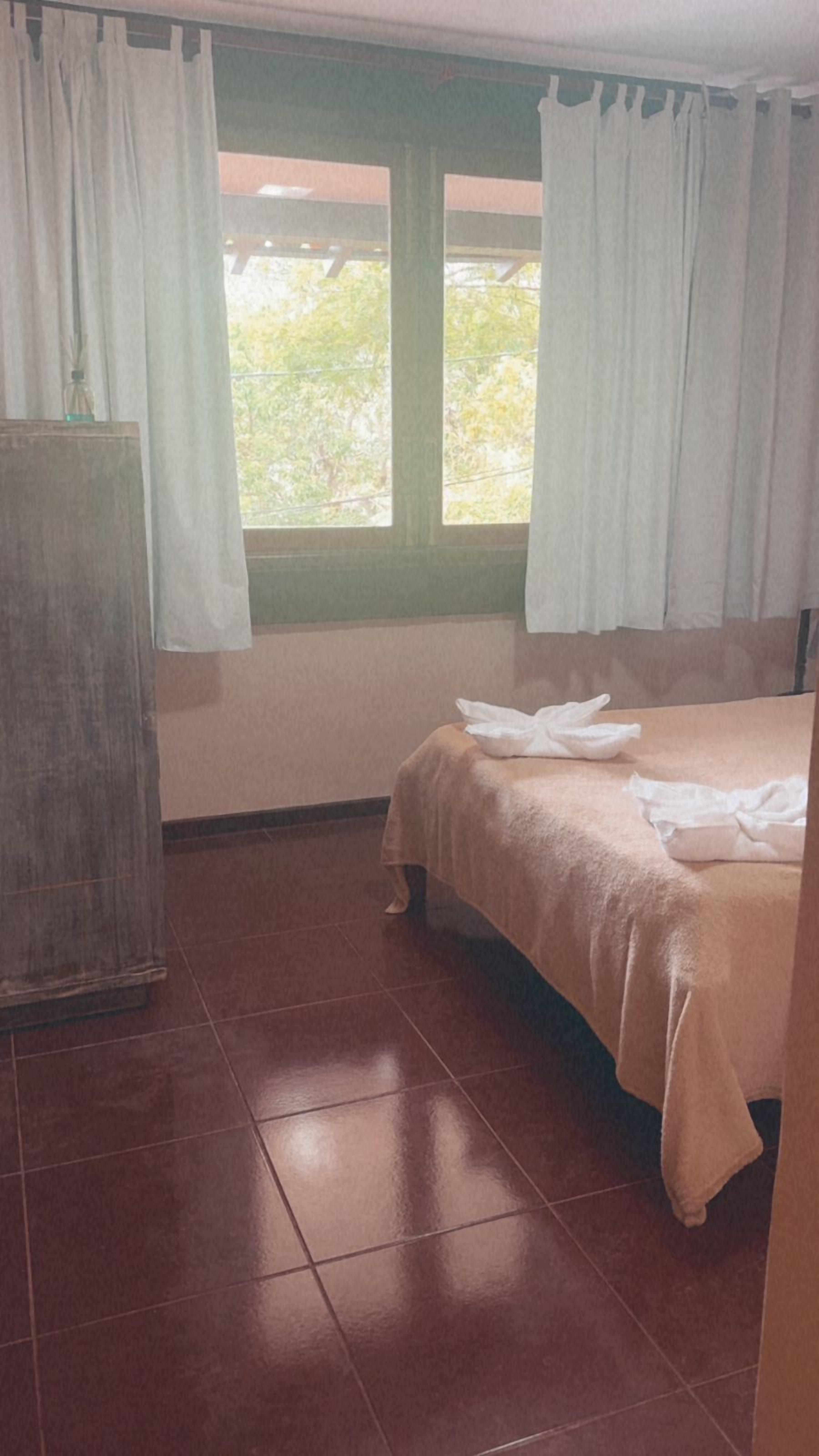 A room with a bed, a wooden wardrobe, and a window with curtains.