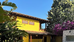 A serene pool area with a statue, a yellow building, and a patio with lounge chairs. - Sheiton Búzios (Búzios)