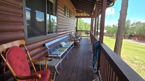 Une cabane en bois dotée d’un porche couvert, d’un espace salon extérieur et offrant une vue sur le paysage environnant.