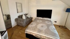 A bedroom with a bed, a sofa, a mirror, and a ceiling light. - K Sweets Bromley Apartments (Bromley)