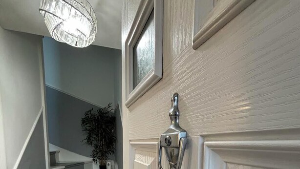 A staircase with a handrail, a door with a silver handle, and a hanging light fixture. - K Sweets Bromley Apartments (Bromley)