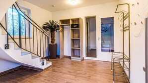 A modern interior with a wooden staircase, a potted plant, a built-in wardrobe, and a metal rack. - Luxuriose Ferienwohnung am Stormthaler See (Grossposna)