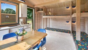 A wooden interior with a dining table, chairs, a window, and a colorful play area. - 4 Person Holiday Park Home in Graested (Graested)