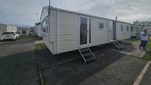 A mobile home with a satellite dish, a sliding door, and a small window. - Ruby a Modern Caravan in Rhyl (Rhyl)