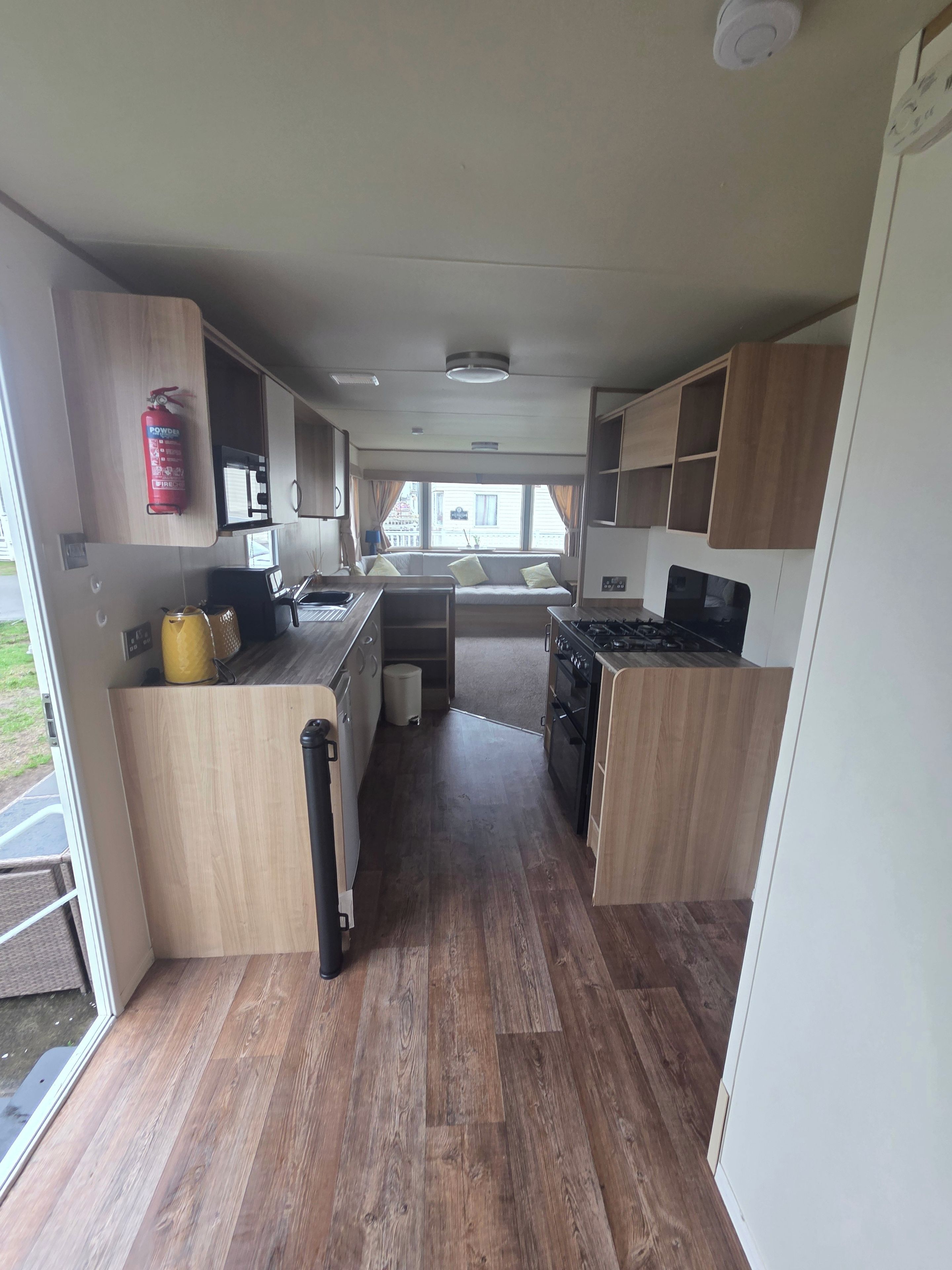 A compact kitchen with wooden cabinets, a stove, and a sink.