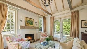 Een gezellige woonkamer met een open haard, fauteuils met bloemenprint en een comfortabele bank.