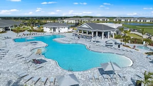 A resort with a large pool area, multiple lounge chairs, and a view of the surrounding landscape. - Gated area, Golfing, HOA Pool, Pickleball Courts, and Family Fun (Ave Maria)