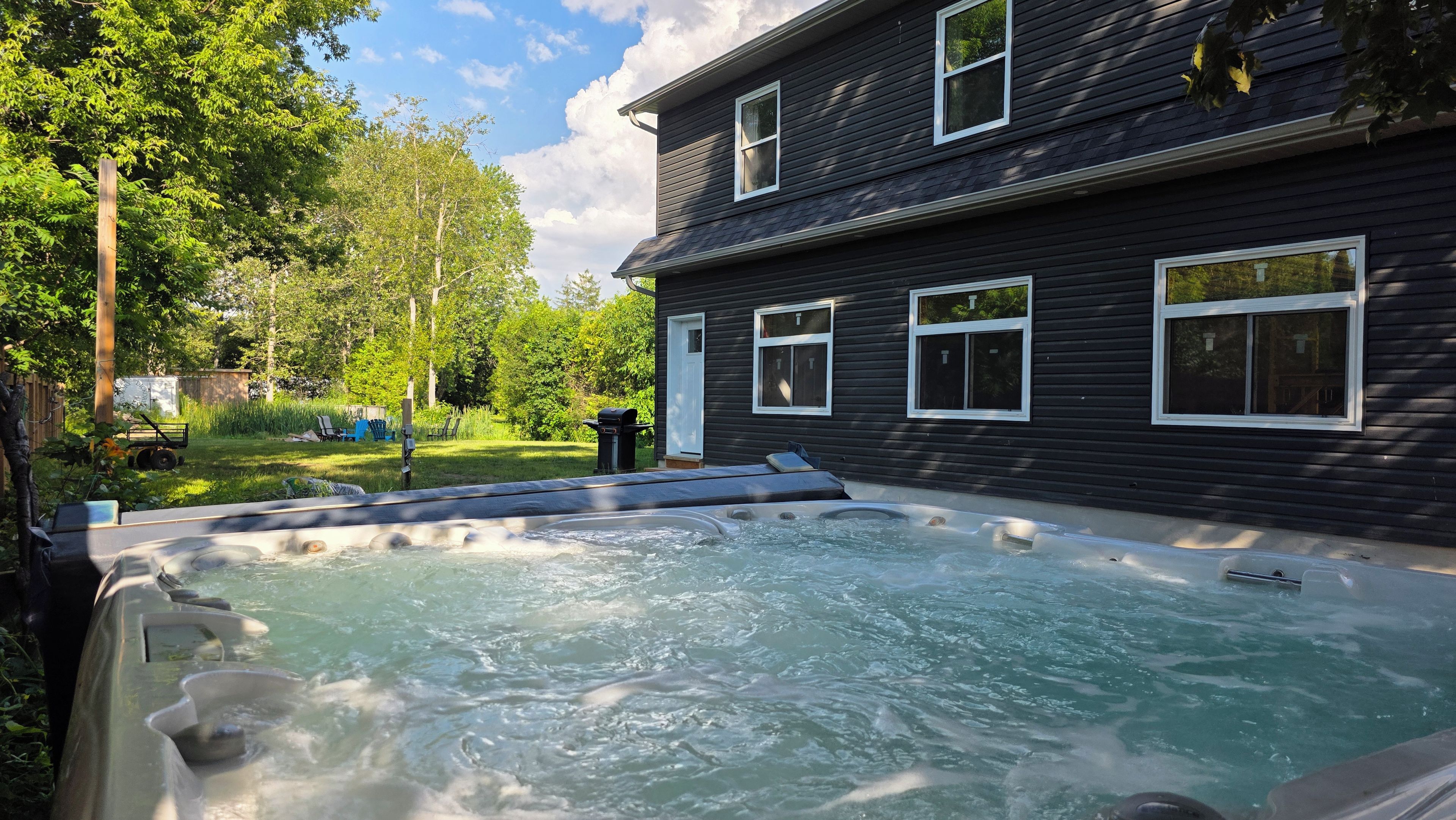 Un bain à remous dans un jardin, avec une maison en arrière-plan.
