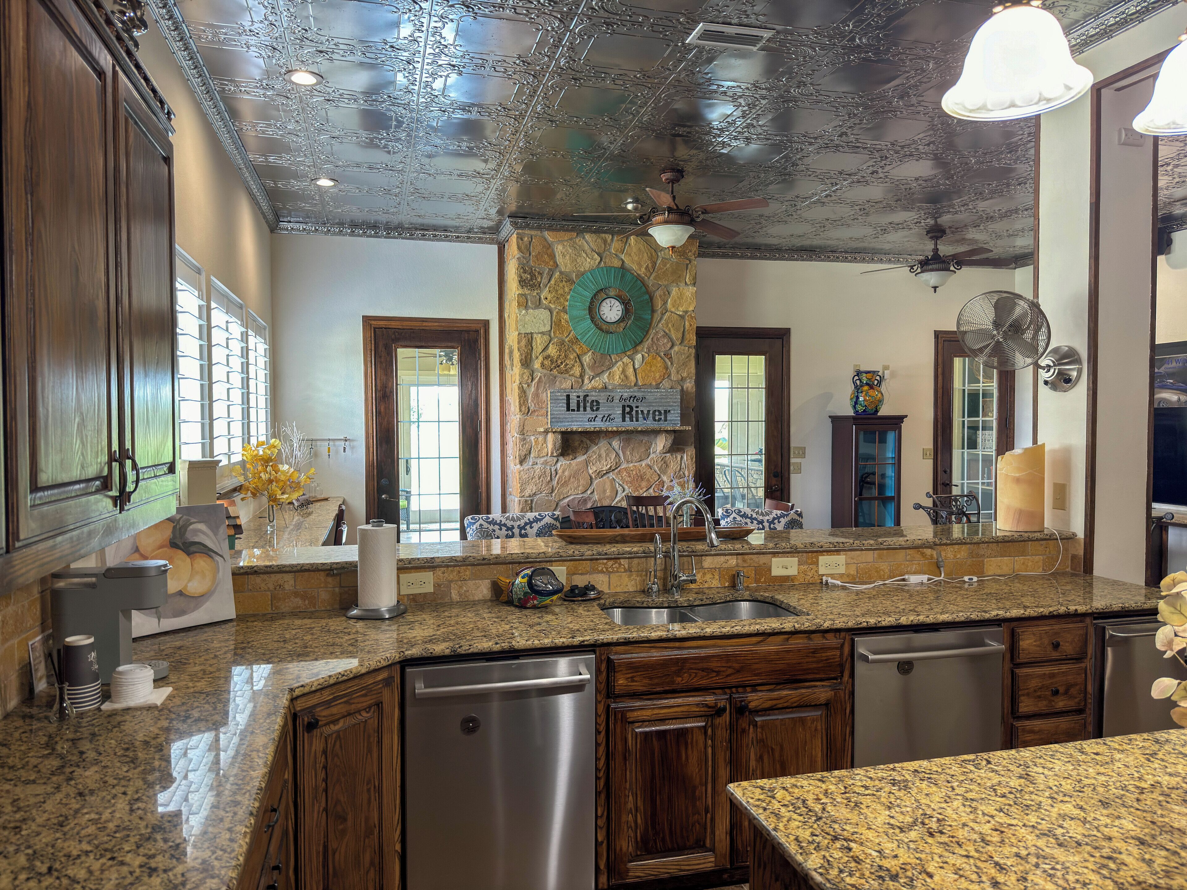 A kitchen with granite countertops, stainless steel appliances, and a stone fireplace.