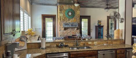 A kitchen with granite countertops, stainless steel appliances, and a stone fireplace.