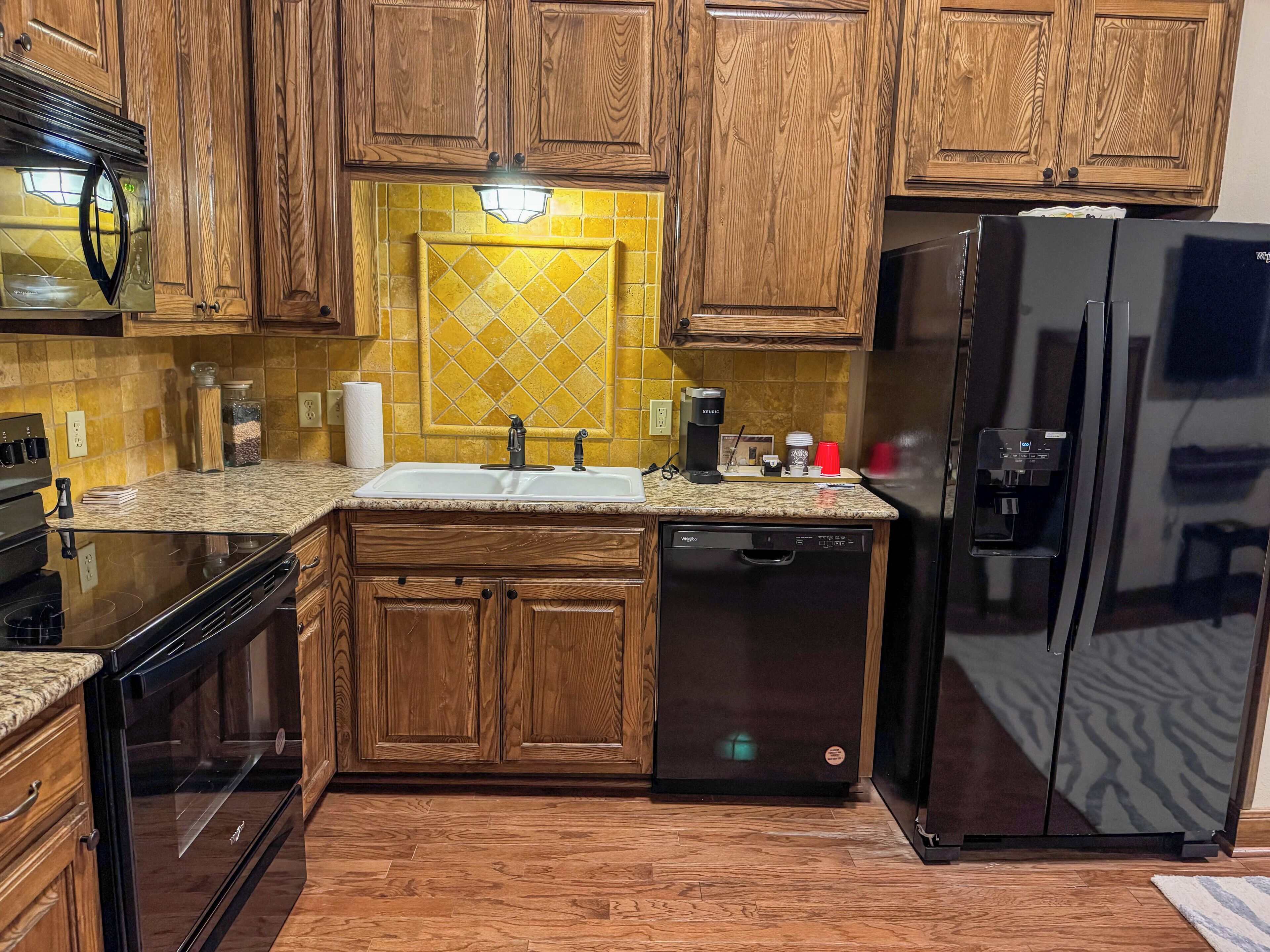 A kitchen with wooden cabinets, a stainless steel refrigerator, a dishwasher, and a coffee maker.