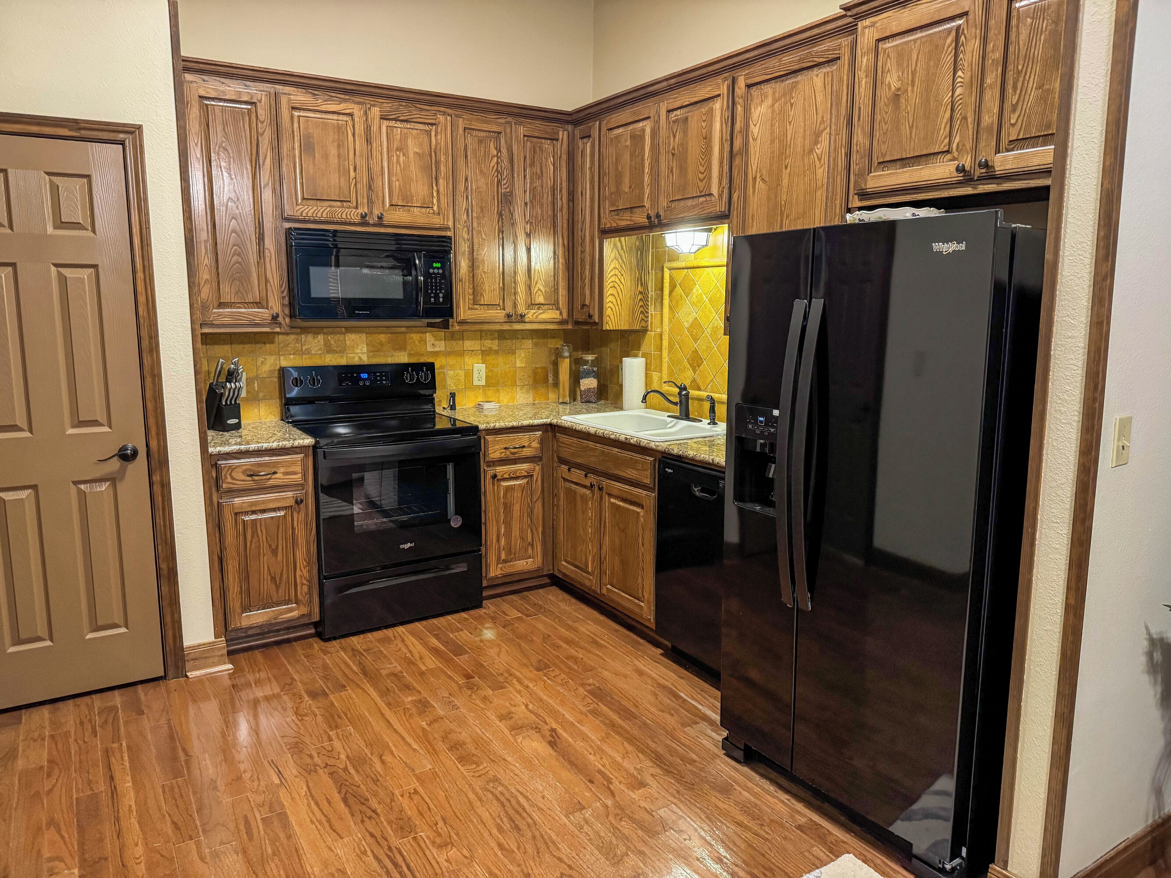 A kitchen with wooden cabinets, a black refrigerator, a microwave, a stove, and a dishwasher.