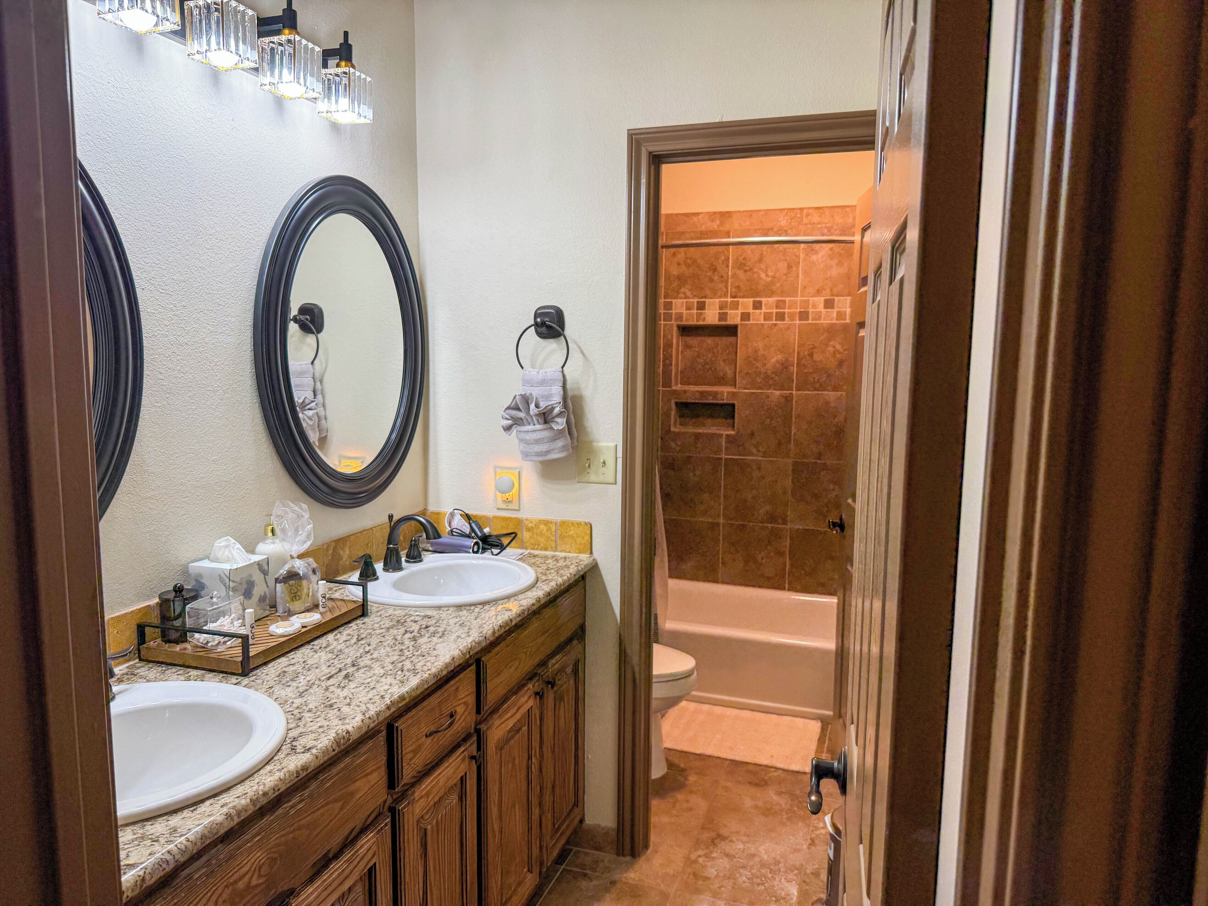 A bathroom with two sinks, a large mirror, and a shower area.
