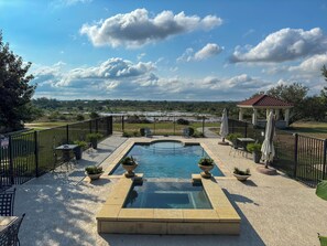 A pool area with a view of a river and a gazebo.