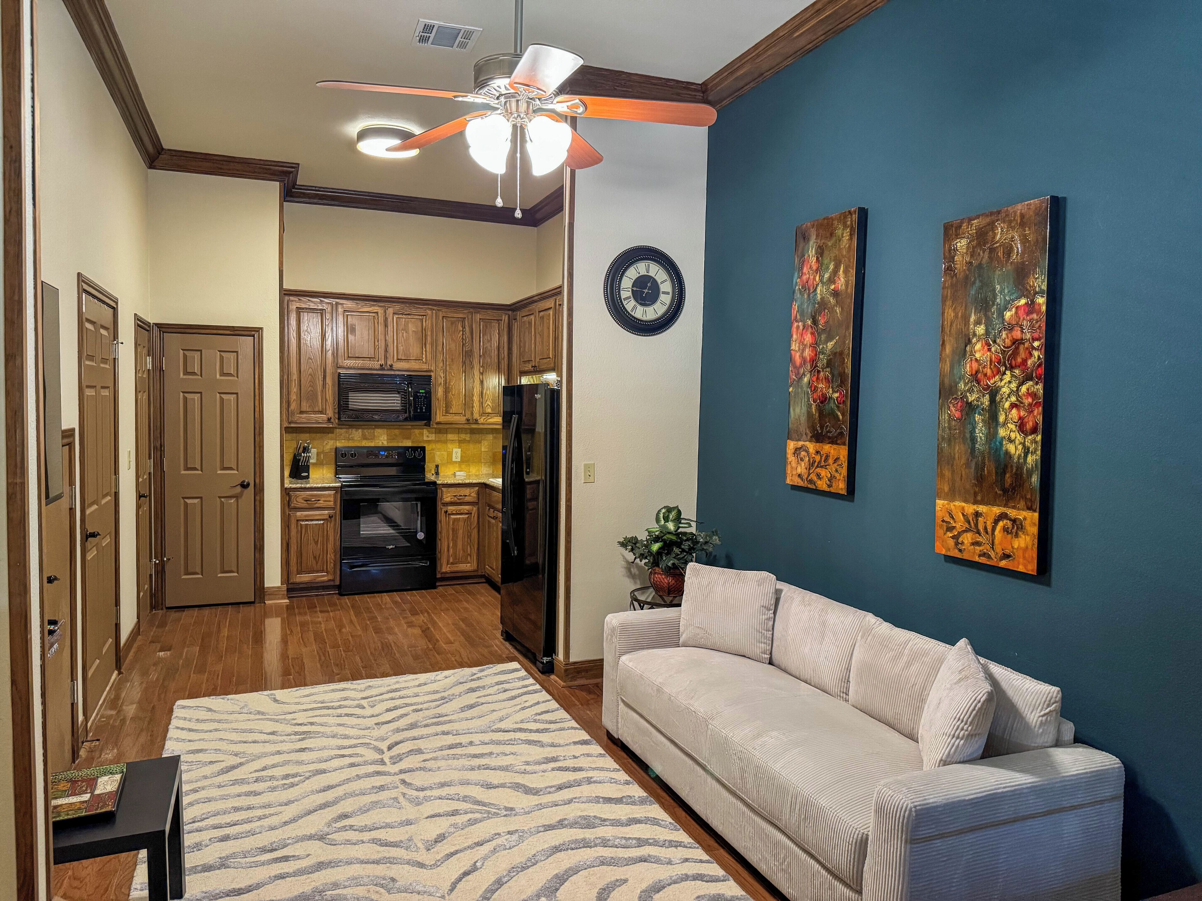 A living room with a sofa, a coffee table, a rug, and a ceiling fan.