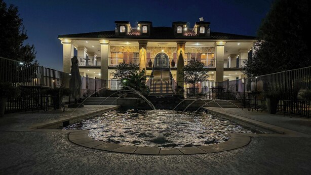 A large, multi-story building with a central courtyard featuring a water fountain. - Bliss On The River (Llano)