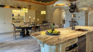 A spacious kitchen with a large island, stone walls, and modern lighting fixtures. - Bliss On The River (Llano)