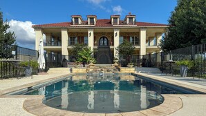 A large, two-story building with a central pool, stone steps leading to the entrance, and a red-tiled roof. - Bliss On The River (Llano)