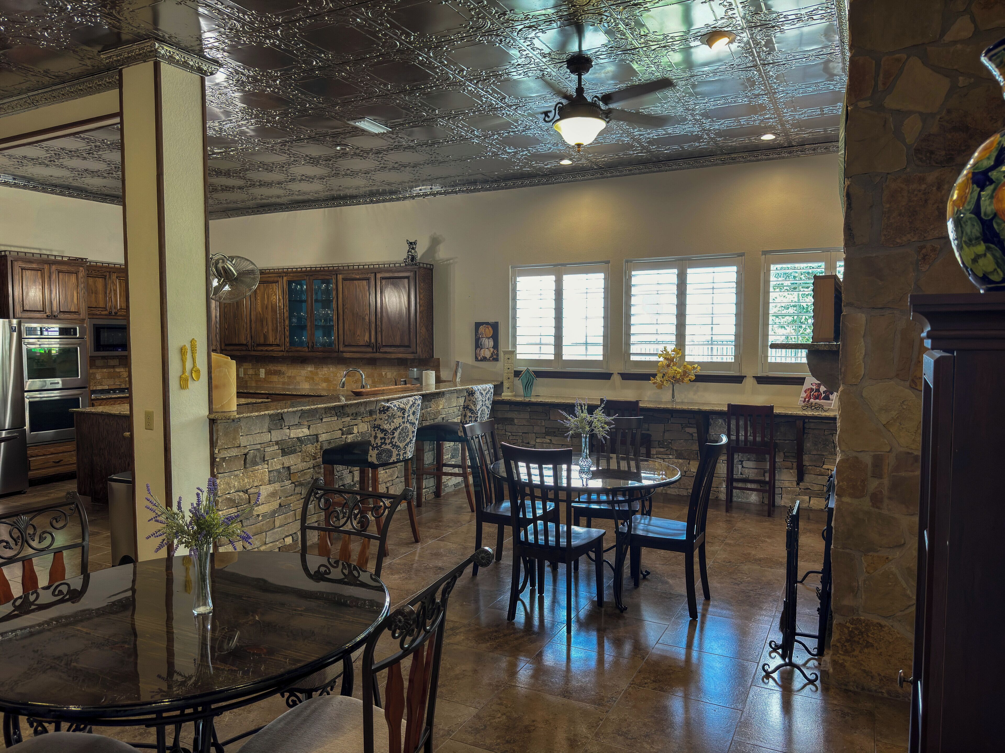 A spacious kitchen with wooden cabinets, a stone countertop, and a dining area with a round table and chairs.