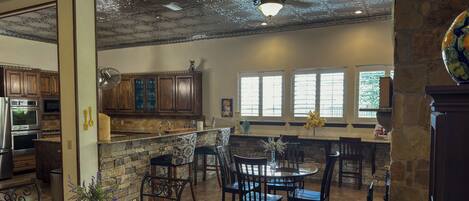 A spacious kitchen with wooden cabinets, a stone countertop, and a dining area with a round table and chairs.