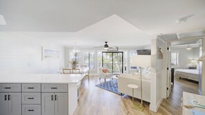 A bright, open-plan living area with a kitchen, dining space, and a bedroom. - Triton Balcony w/ Pool View, Chic Design (Santa Rosa Beach)