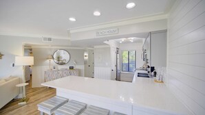 Una cocina moderna con una isla grande, taburetes de bar y un cartel que dice "Beach House".