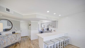 Una cocina moderna con armarios blancos, una isla grande con taburetes de bar y un espejo redondo sobre el mostrador.
