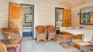 A cozy cabin interior with wooden walls, a dining table, wicker chairs, and a glass table.